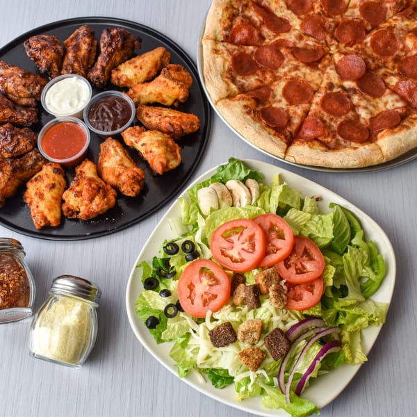 A pepperoni pizza, a platter of chicken wings with dipping sauces, and a fresh garden salad.