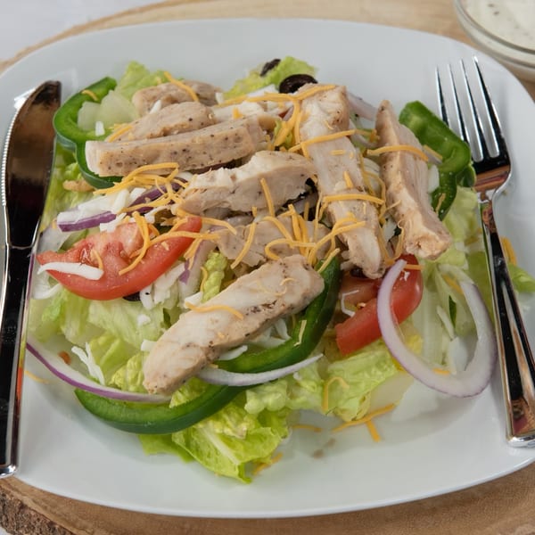 Chicken salad with lettuce, tomatoes, onions, green peppers, cheese, and black olives.