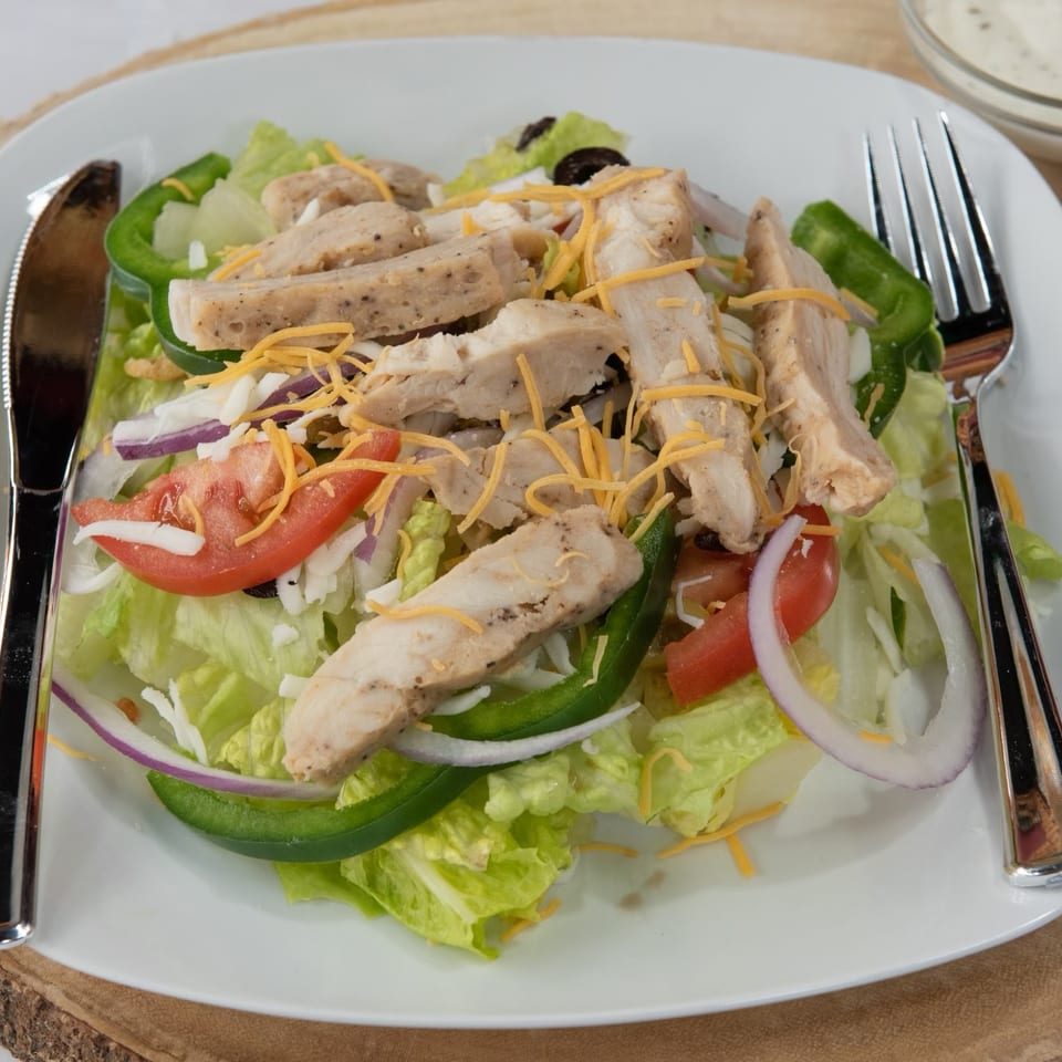 Chicken salad with lettuce, tomatoes, onions, green peppers, cheese, and black olives.