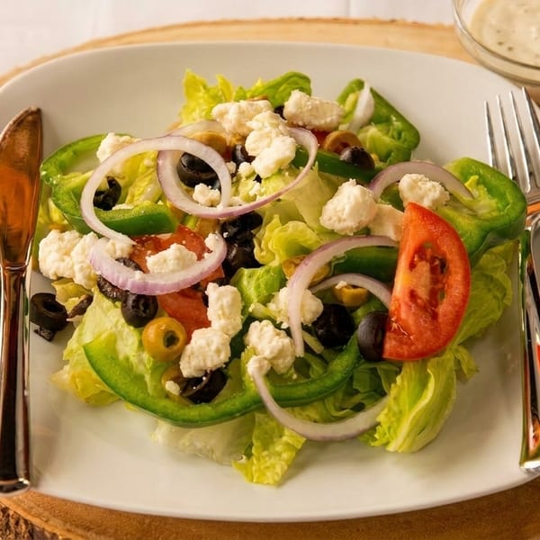 Fresh garden salad with lettuce, tomatoes, onions, olives, green peppers, and feta cheese.