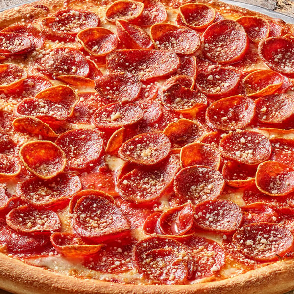 A large, round pepperoni pizza with a thick crust, sprinkled with parmesan cheese, on a metal pan.